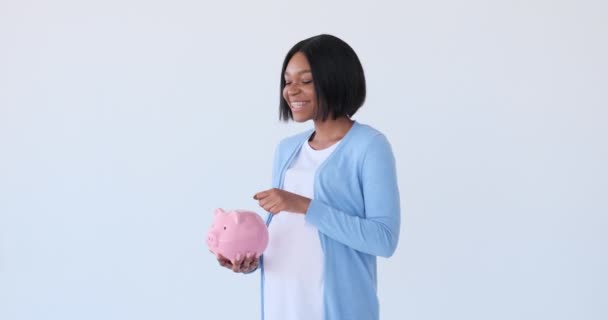 Pregnant woman inserting coin into piggy bank — Stock Video