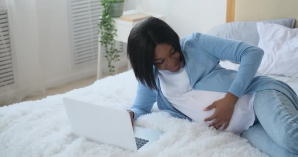 Ciężarna kobieta korzystająca z laptopa w łóżku — Wideo stockowe