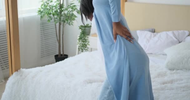 Вагітна жінка масажує спину на ліжку — стокове відео