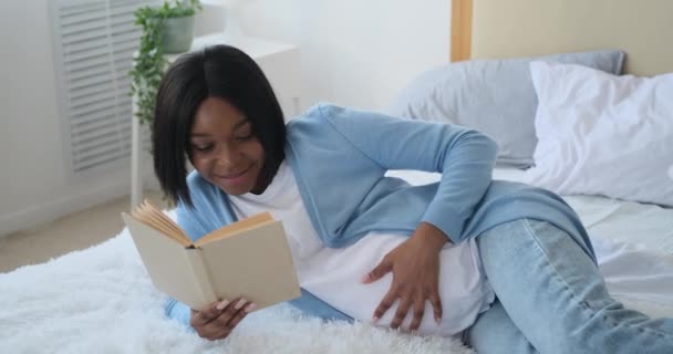 Schwangere liest Buch zu Hause im Bett — Stockvideo