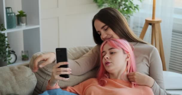 Lesbičky pár pomocí mobilního telefonu ležící na pohovce — Stock video