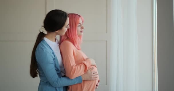 Kvinna och hennes gravida flickvän tittar ut genom fönstret — Stockvideo