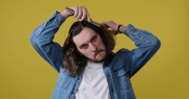 Мужчина расчесывает волосы на жёлтом фоне — стоковое видео