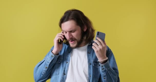 Frustrated man talking on two mobile phones — Stock Video