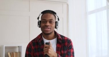 Mutlu adam evde dans ederken uzaktan kumandayla şarkı söylüyor.