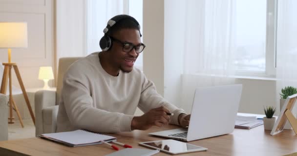 Человек слушает музыку и использует ноутбук в домашнем офисе — стоковое видео
