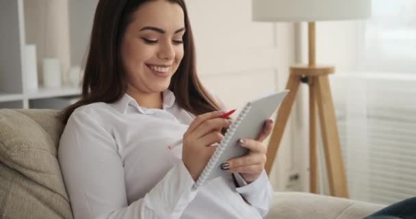 Excited woman preparing shopping list in notepad — Stock Video