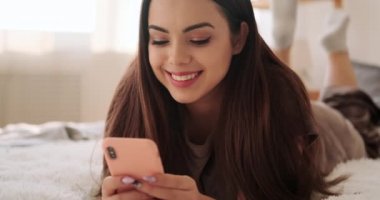 Yatakta cep telefonu kullanan kadın.