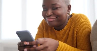 Kanepede uzanan ve cep telefonu kullanan bir kadın.