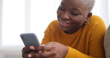 Kanepede uzanan ve cep telefonu kullanan bir kadın.