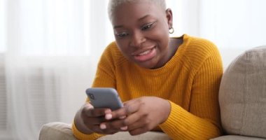 Kanepede uzanan ve cep telefonu kullanan bir kadın.