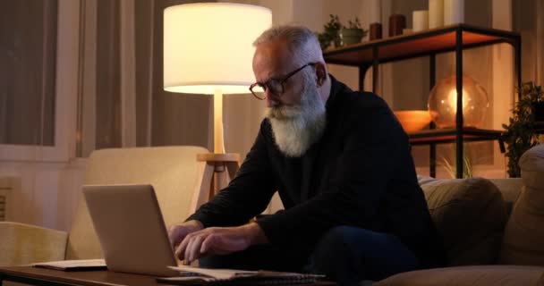 Κουρασμένος ηλικιωμένος άνδρας κλείνει το laptop σηκώνοντας αργά το βράδυ — Αρχείο Βίντεο