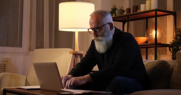 Hombre mayor cansado trabajando hasta tarde en el portátil — Vídeos de Stock