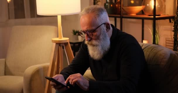 Oude man sms 'en met behulp van mobiele telefoon laat op de avond — Stockvideo