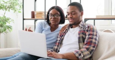 Çift kanepede dizüstü bilgisayar kullanıyor.