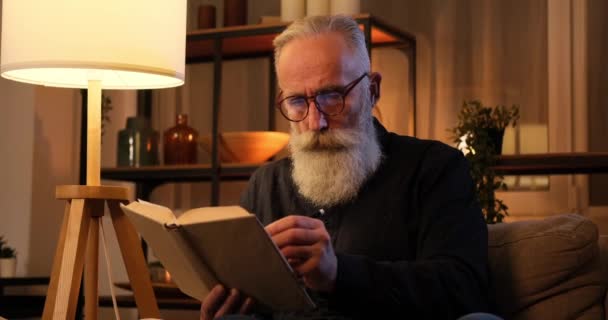 Ο γέρος μαρκάρει με στυλό ενώ διαβάζει ένα βιβλίο. — Αρχείο Βίντεο