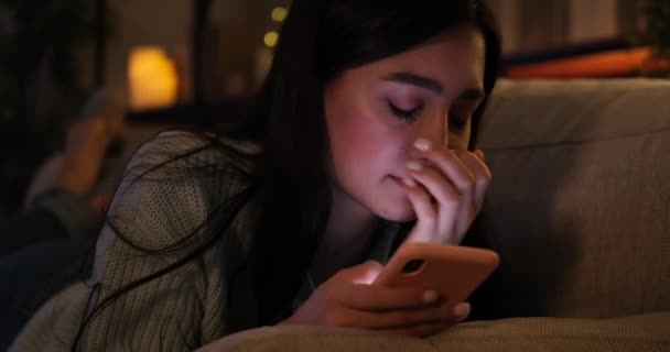 Yorgun bir kadın cep telefonu kullanıyor ve geç saatlere kadar kanepede uyuyor. — Stok video