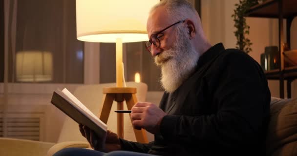 Viejo leyendo un libro y marcando con bolígrafo — Vídeos de Stock