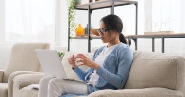 Dizüstü bilgisayarda çalışan ve evde notlar yazan bir kadın.