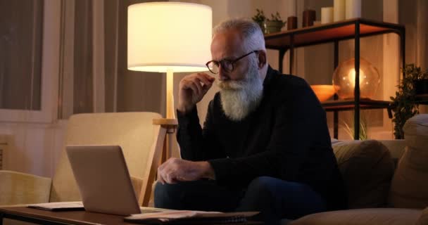 Hombre girando bigote y el análisis de documentos utilizando el ordenador portátil — Vídeos de Stock