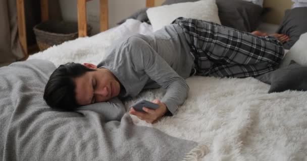 Pozorný muž ležící na posteli a používající mobilní telefon — Stock video