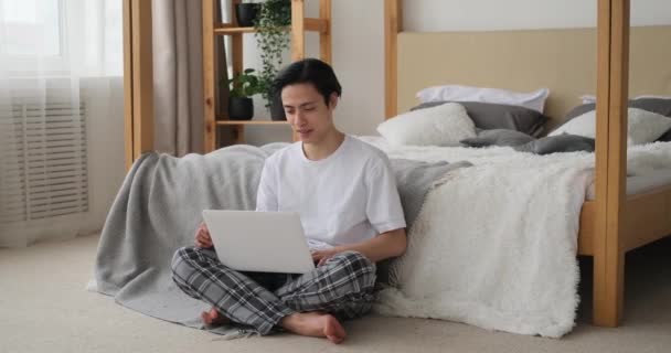 Homme heureux en utilisant un ordinateur portable dans la chambre — Video