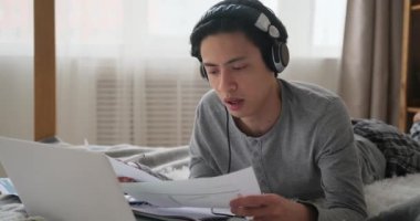 Adam bilgisayar ve kulaklık kullanarak video görüşmeleri yapıyor.