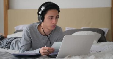 Yatakta video konferansı için dizüstü bilgisayar kullanan adam