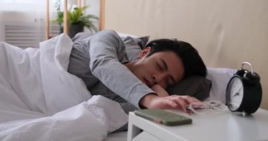 Adam uyanıyor ve cep telefonunu kontrol ediyor.