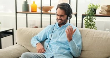 Kulaklıklı bir adam gitar çalıyor.