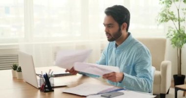 Ciddi bir adam video sohbeti yapıyor ve kağıtları dağıtıyor.