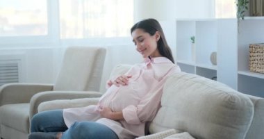 Happy pregnant woman caressing her belly