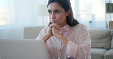 Thoughtful woman with laptop at office