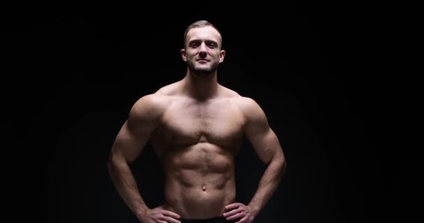 Muscular man posing with arms akimbo — стоковое видео