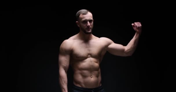 Man flexing biceps in studio — Stock Video