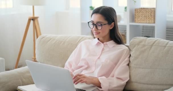 Boldog asszony használ laptop a kanapé — Stock videók