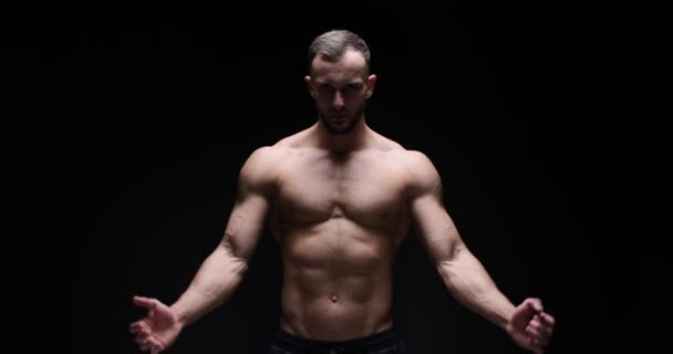 Man flexing biceps in studio — Stockvideo