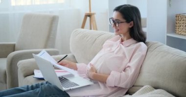 Young pregnant woman using laptop for video calling