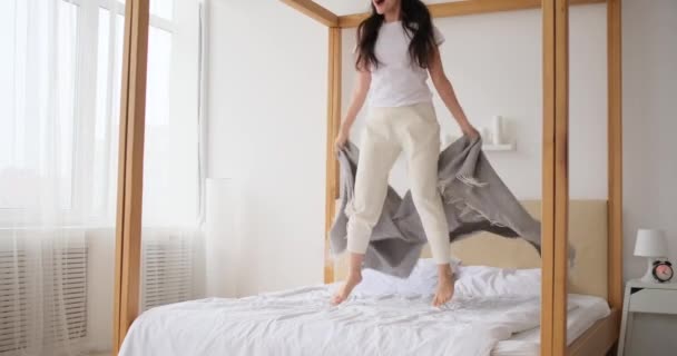 Spännande kvinna hoppar på sin säng — Stockvideo