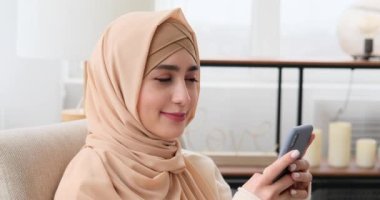 Evde cep telefonu kullanan düşünceli bir kadın.