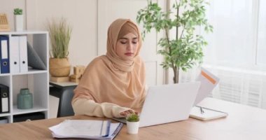 Ofiste dizüstü bilgisayar kullanan ve belgeyi analiz eden kadın