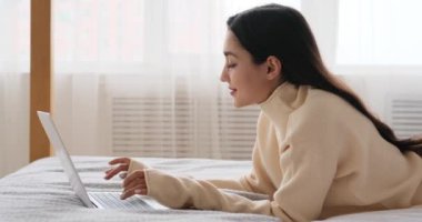 Yatakta dizüstü bilgisayar kullanan bir kadın.