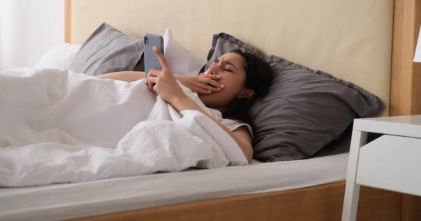 Жінка використовує мобільний телефон і спить на ліжку — стокове відео