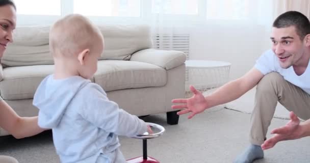 Os pais se divertindo com o bebê menino montando carro de brinquedo — Vídeo de Stock