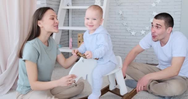 Eltern haben Spaß mit Baby, das auf schaukelndem Hirsch spielt — Stockvideo