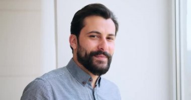 Genç adam gülümsüyor ve pencereden dışarı bakıyor.