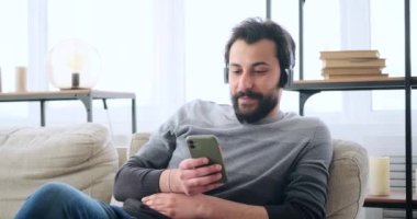 Adam koltukta dinlenirken, kulaklıkla müzik dinliyor.