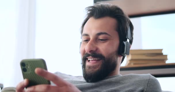 Hombre usando el teléfono móvil y escuchando música en los auriculares — Vídeo de stock