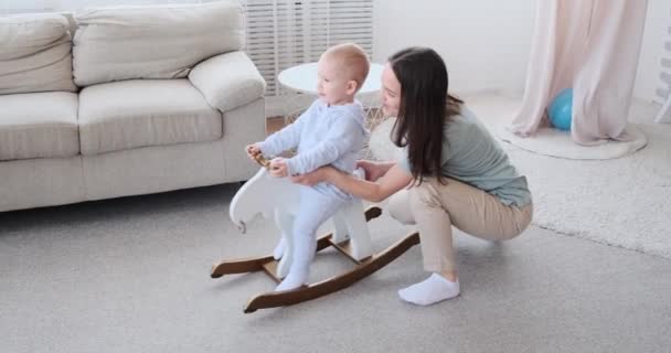 Eltern haben Spaß mit Baby auf schaukelndem Hirsch — Stockvideo