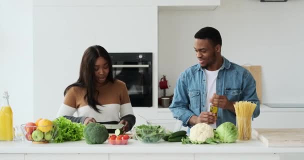 Couple afro-américain discuter tout en préparant la nourriture dans la cuisine — Video